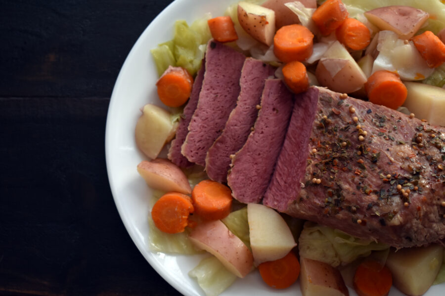 A corned beef brisket on a platter with potatoes, cabbage, and carrots