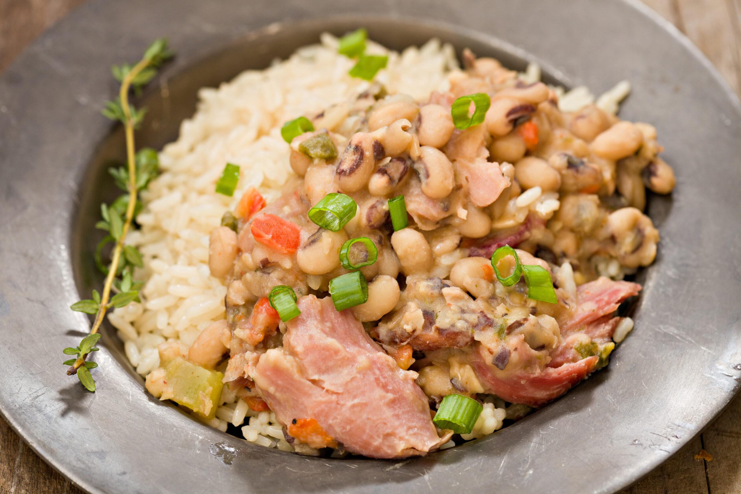 A dish of Hoppin' John, which is cooked black eyed peas, smoked turkey and served over white rice on an old fashioned pewter plate