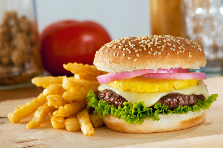 A pineapple gourmet burger served on a wooden surface.