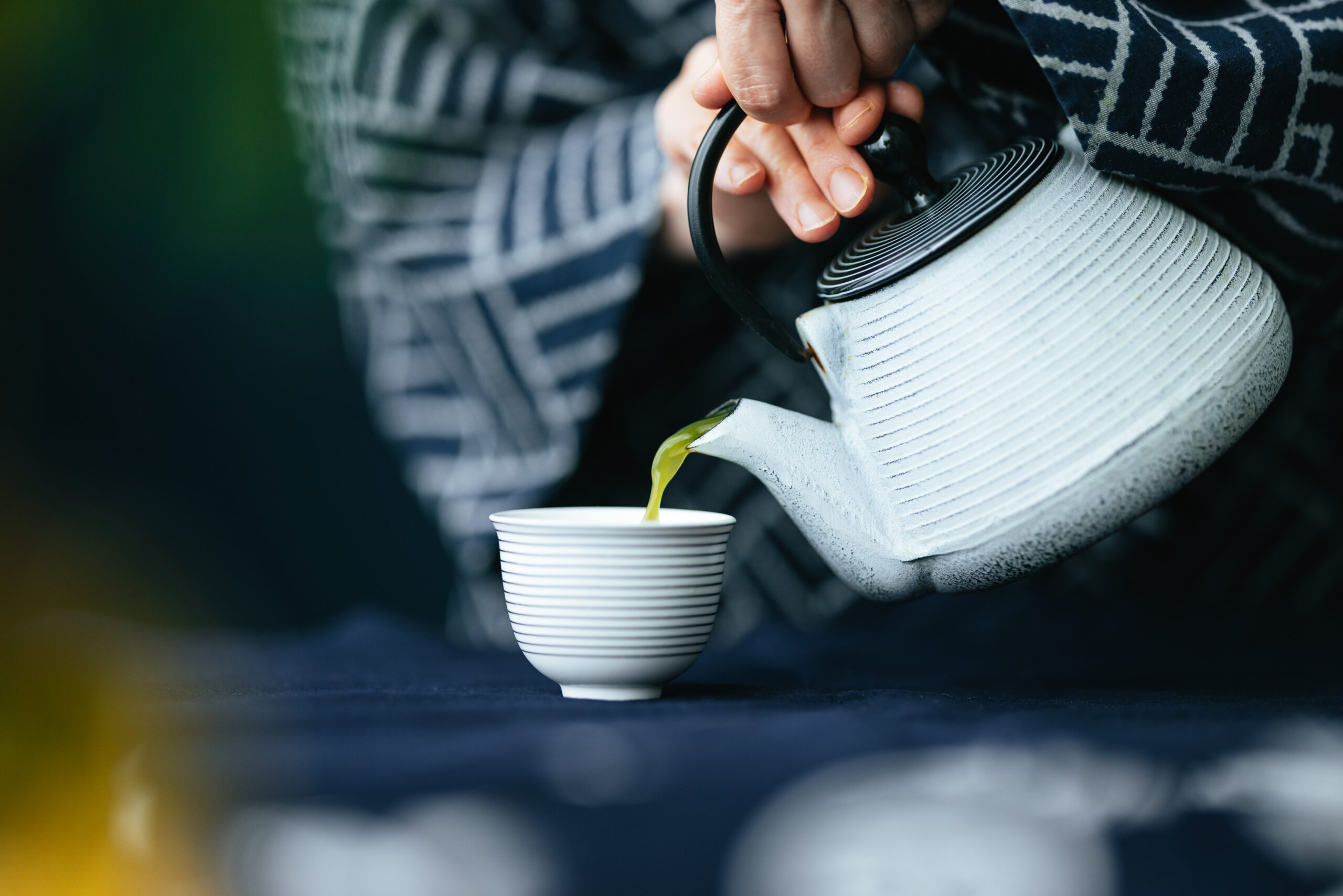 An anonymous Asian woman in kimono preparing cup of hot tea at kitchen desk. at home.