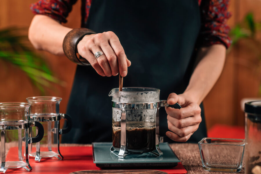 Close up image of hands of barista making French press coffee