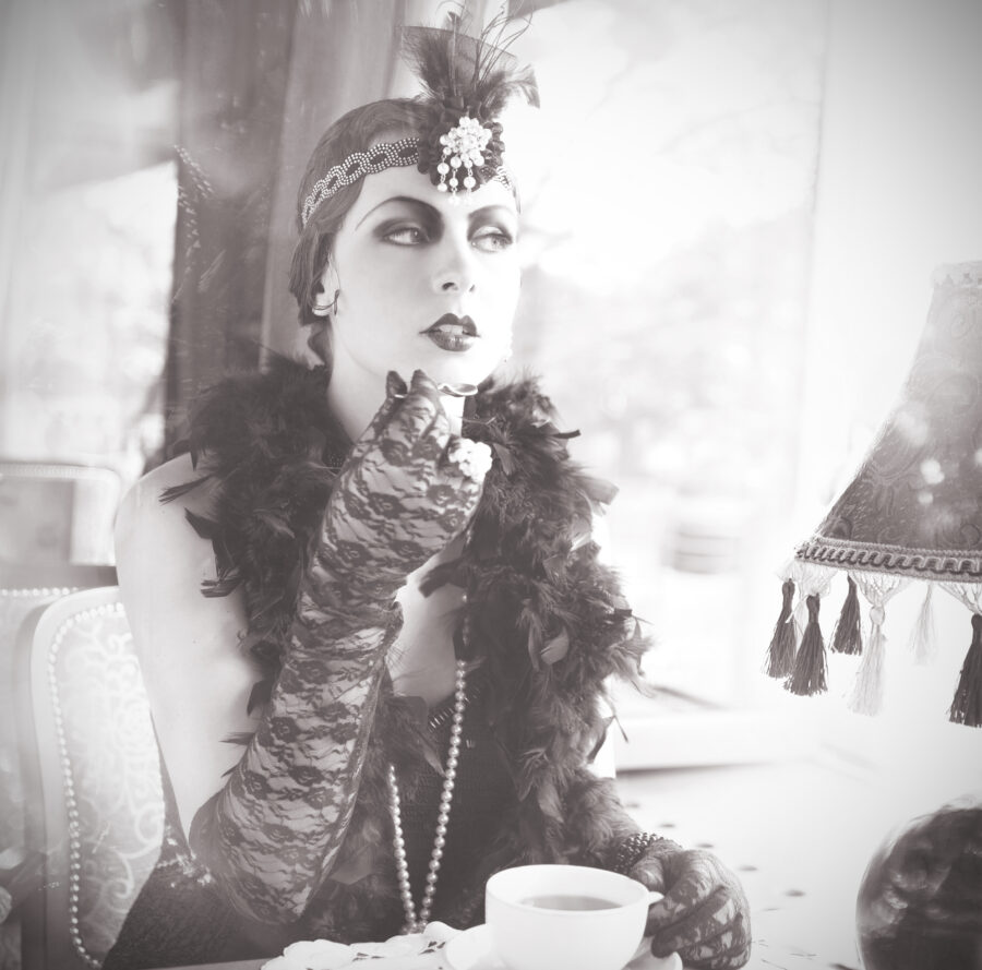 Black and White Portrait of The Beautiful Retro woman Sitting in the Cafe in Black Lace and Accessories  in Style 1920s - 1930s