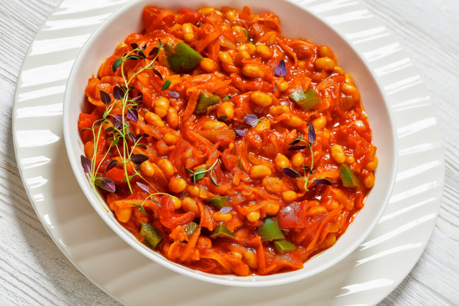 chakalaka, refreshing spicy tomato bean relish in white bowl on white wooden table, South Africa cuisine, close-up