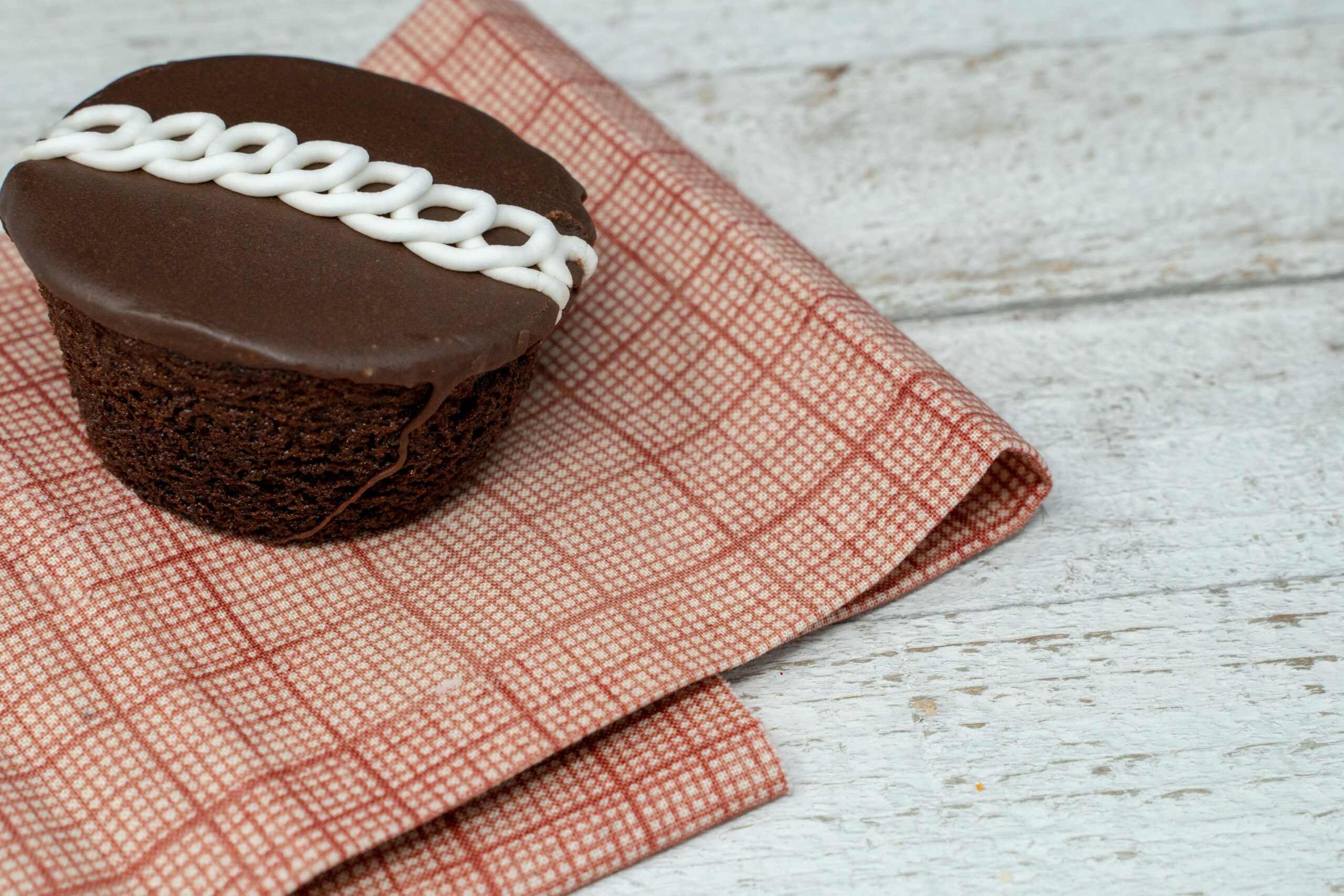 Chocolate swirled decorated cupcake with red napkin on wood background