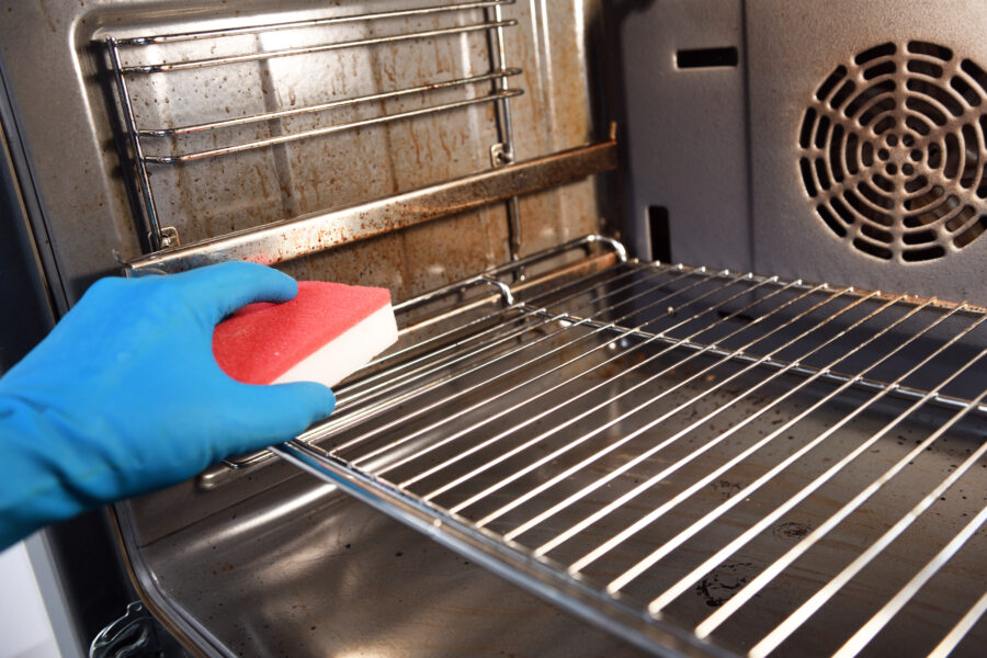 Cleaning the oven. Woman's hand in household cleaning gloves cleans oven inside.