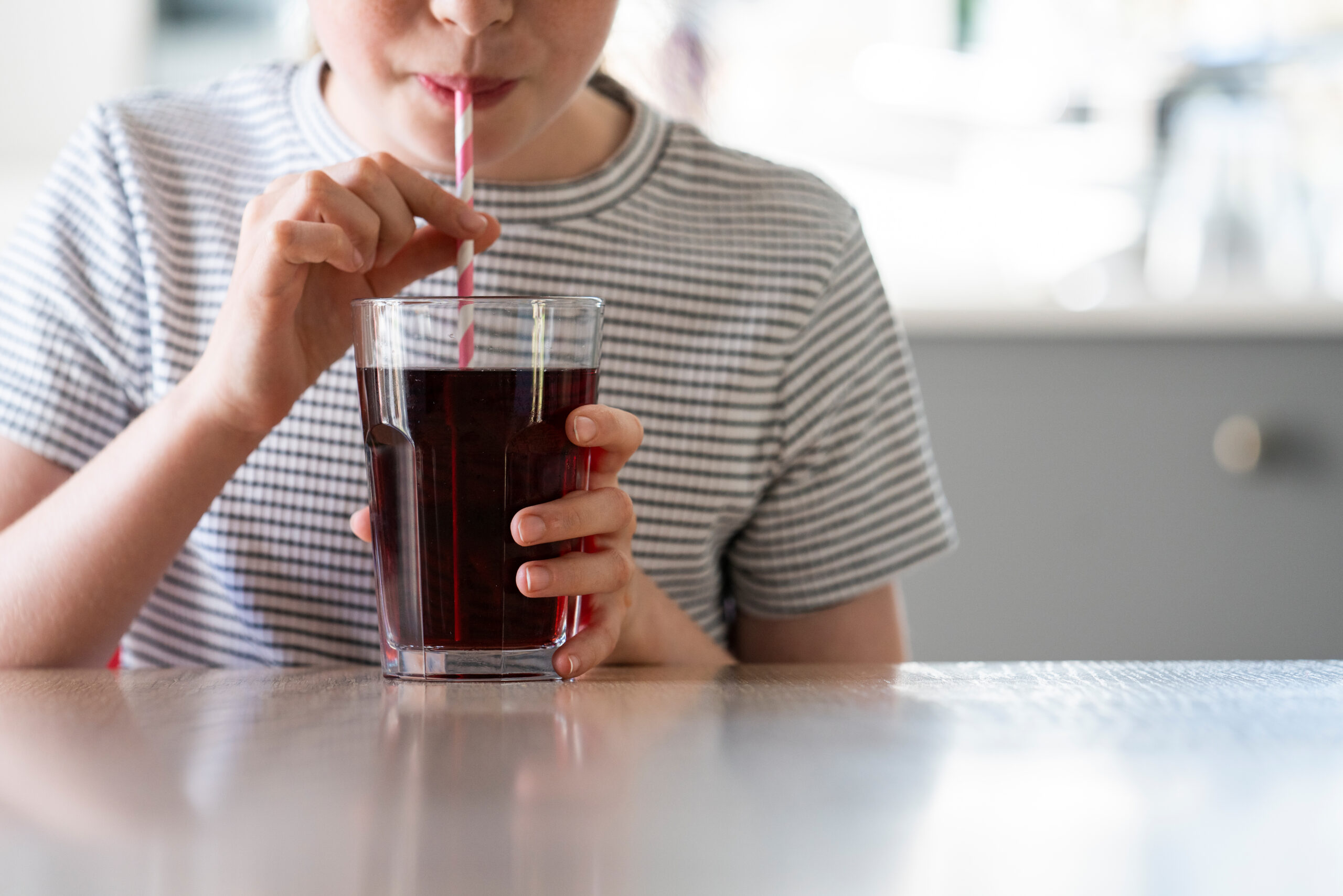 Close Up Of Girl Drinking Sugary Fizzy Soda From Glass With Straw