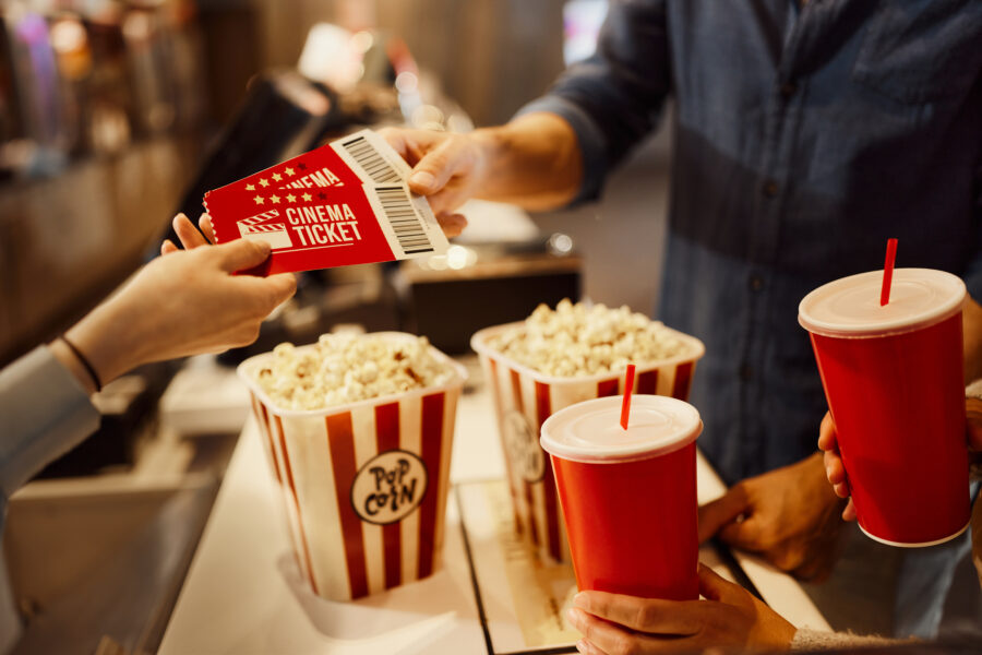 Close up of unrecognizable cashier giving movie tickets to her customer in cinema.