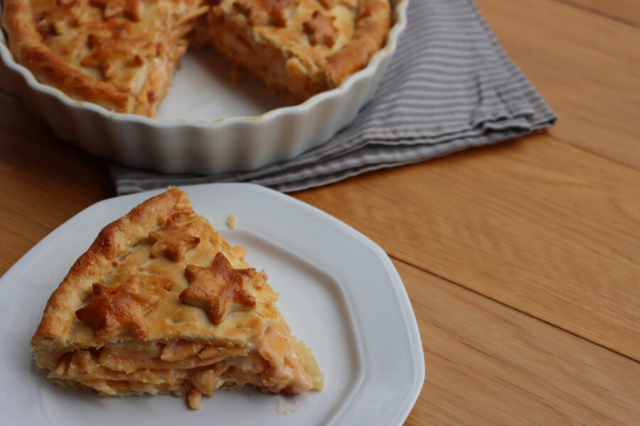 Cut Italian Timballo or Timbale filled with pasta and bechamel with tomato sauce on wooden table