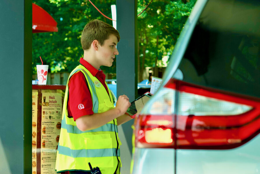 A Chick-fil-A employee takes a customer’s order at the drive through during the lunch hour at the popular fast-food restaurant.