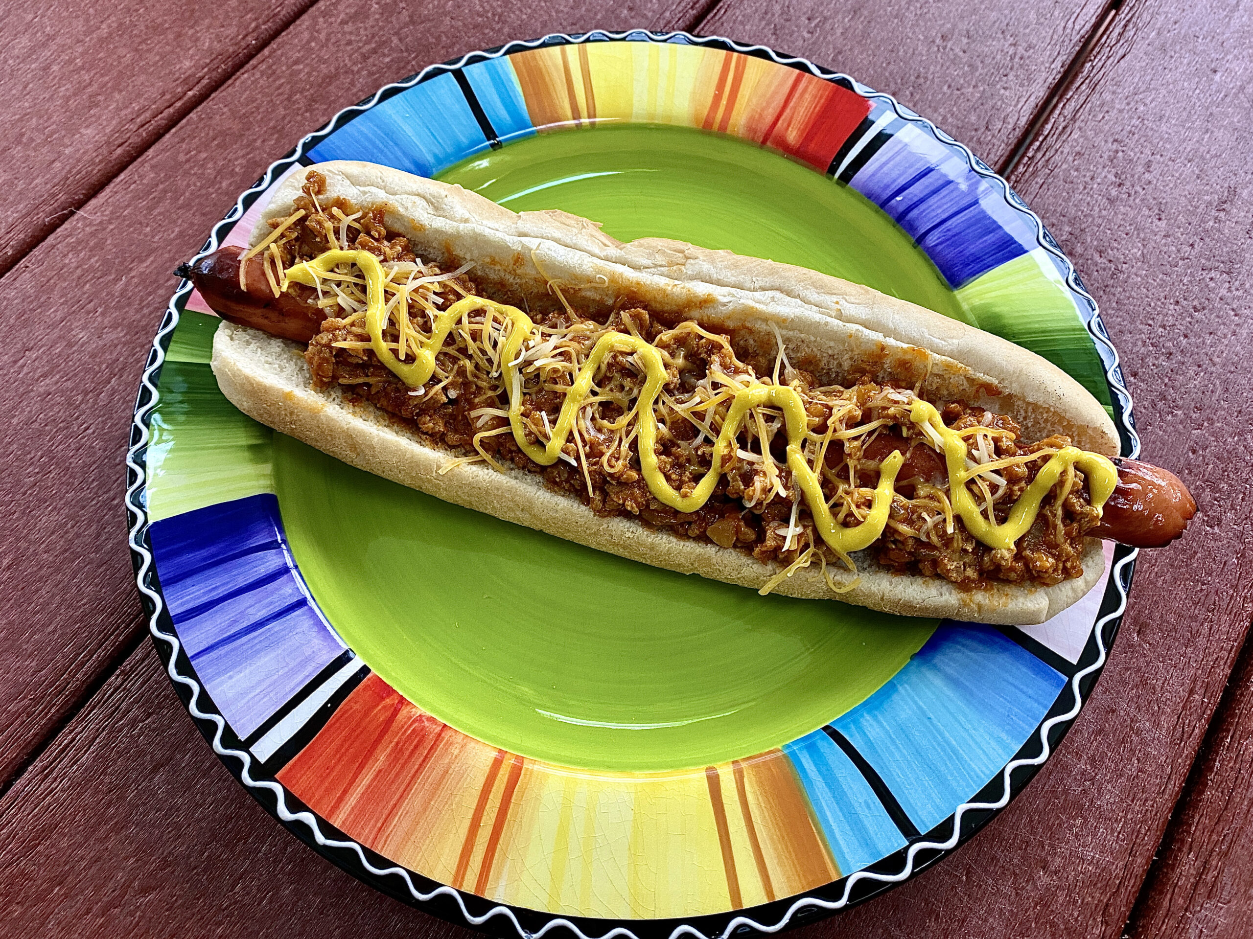 Foot long coney dog on a colorful plate.