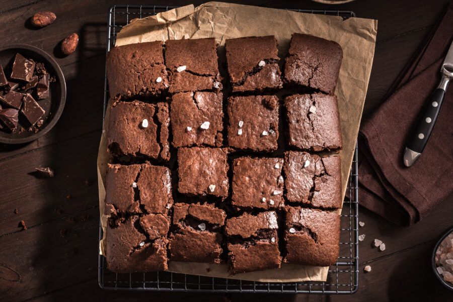 Fresh chocolate brownies on dark wooden table. Delicious homemade chocolate dessert, pie brownie and ingredients, top view, copy space.