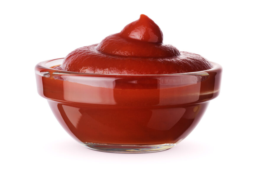 Glass bowl of ketchup or tomato sauce isolated on white background.