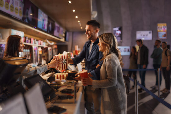 Happy couple buying snack and drinks at concession stand in cinema.