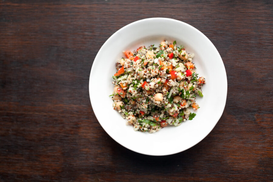 Healthy quinoa salad with chickpeas, bell peppers, cucumbers, onions and parsley.