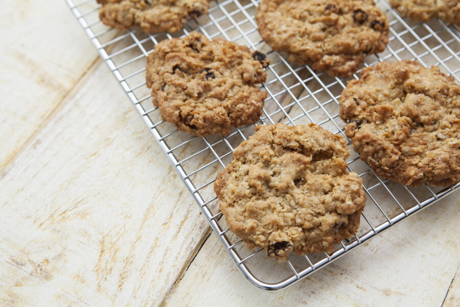 Home baking - wire rack full of rustic looking cookies on a cream coloured, rough wooden table top