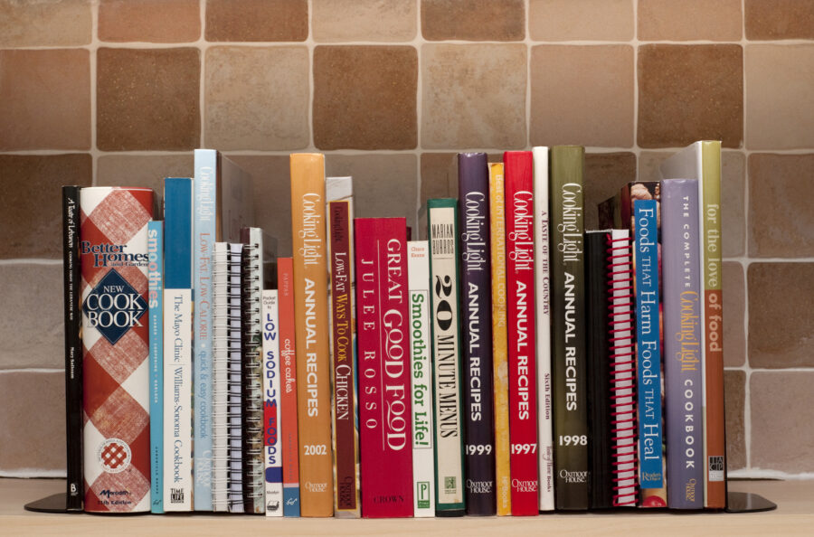 Cookbooks on kitchen shelf.  Cook books include one by Julee Russo a Better Homes Cook book and many cookbooks published by Cooking Light.