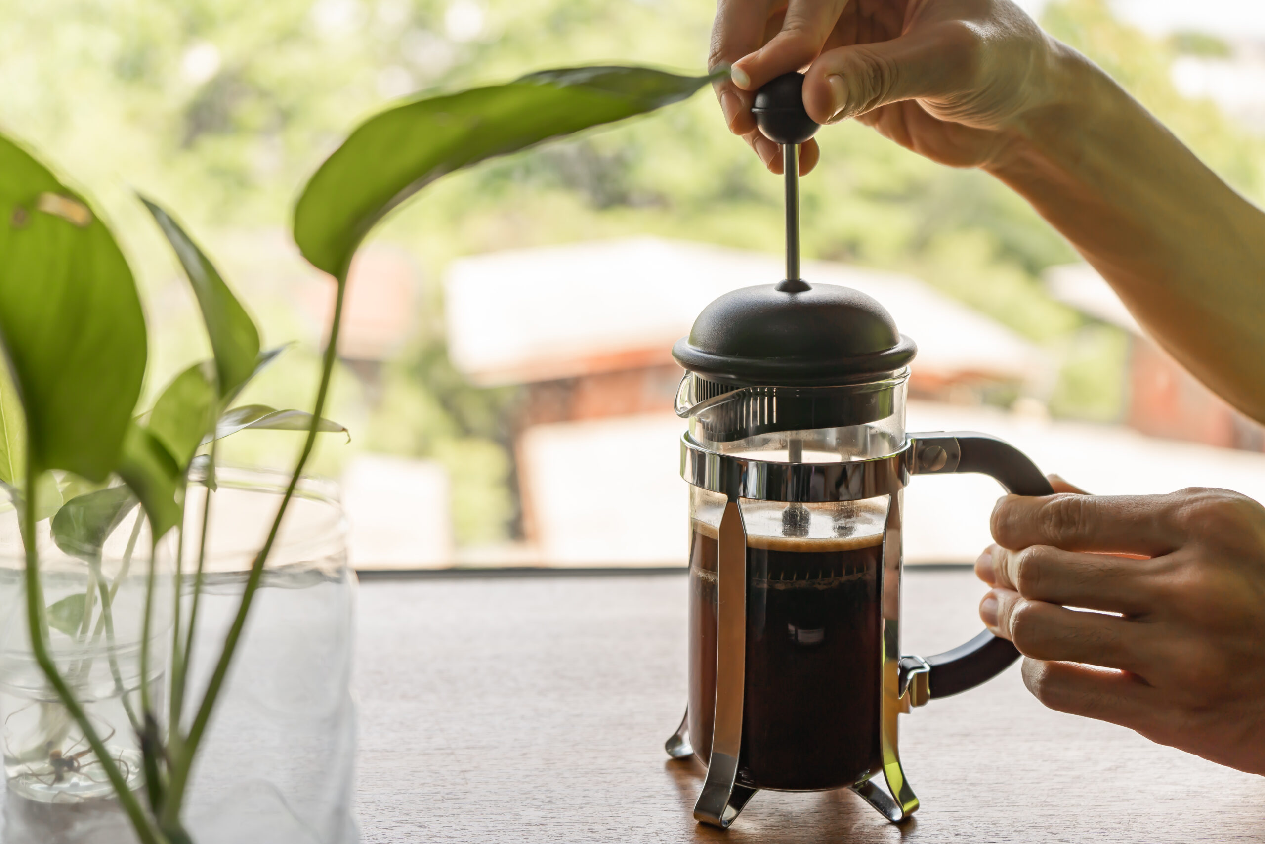 Pressing the plunger of the French press coffee maker down.