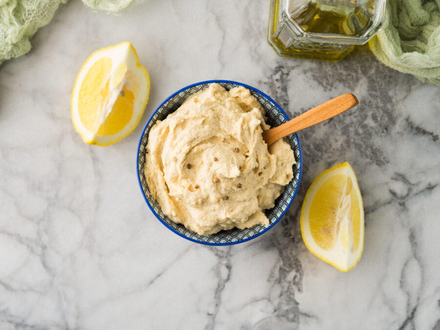 Mashed chickpeas Hummus dip with tahini and lemon juice and oil in bowl on marble board