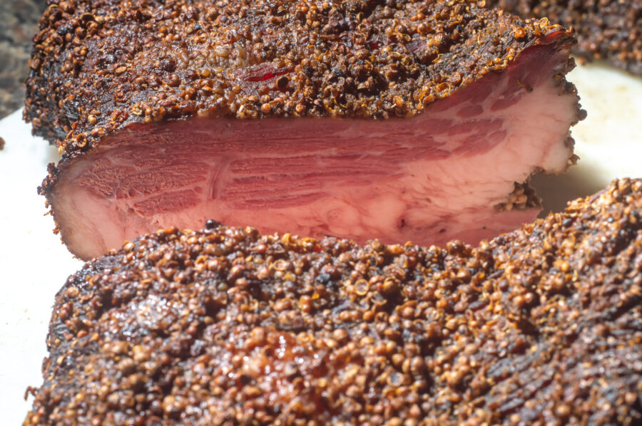 Roasted beef, pastrami on slate cutting board, male hand holding a piece of pastrami,Copy space..