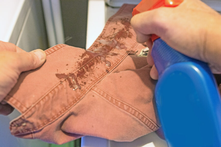 Senior's perspective and view as puts stain remover on shirt prior to putting it in the washing machine. Close-up