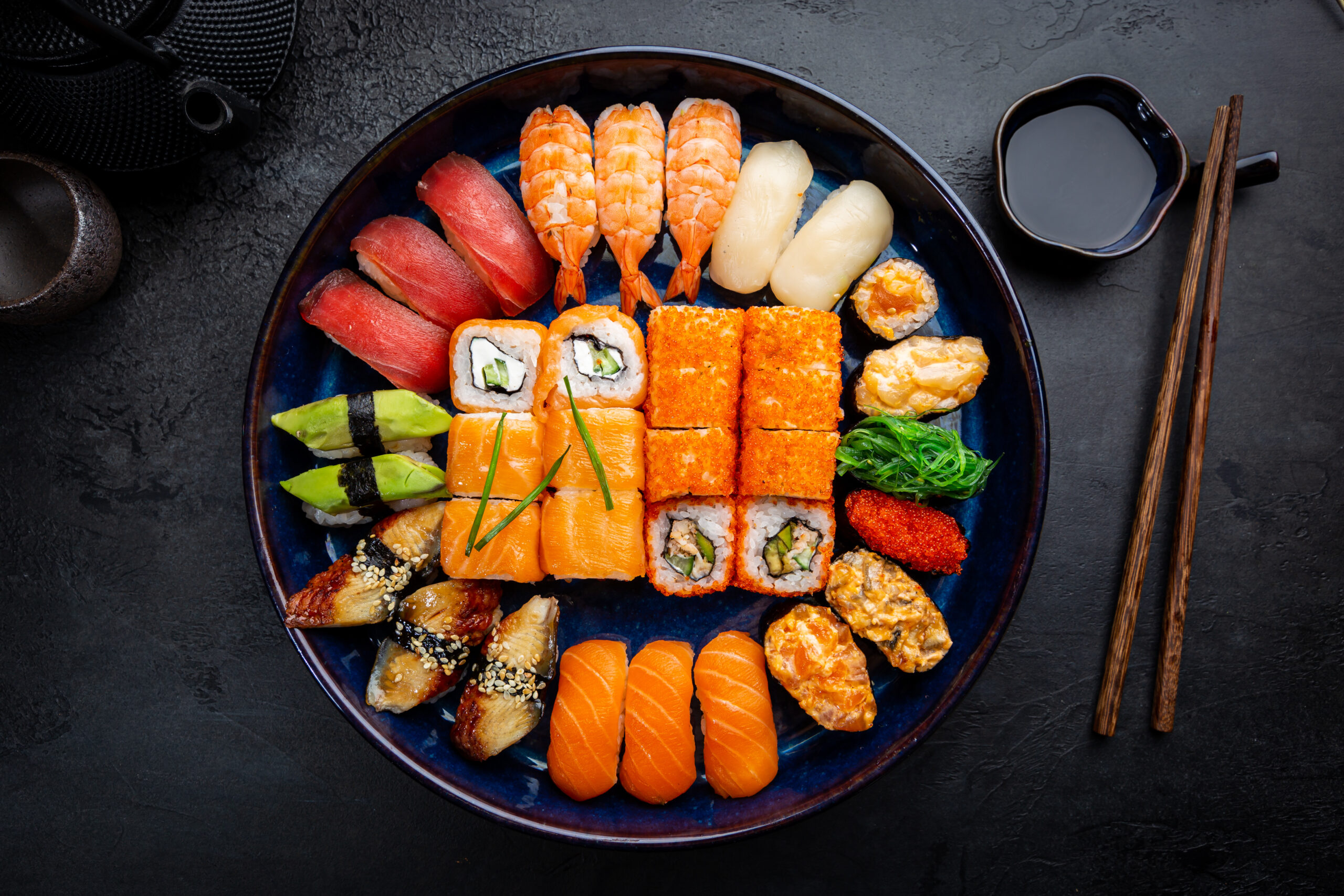 Set of sushi and maki with soy sauce over black background. Top view with copy space