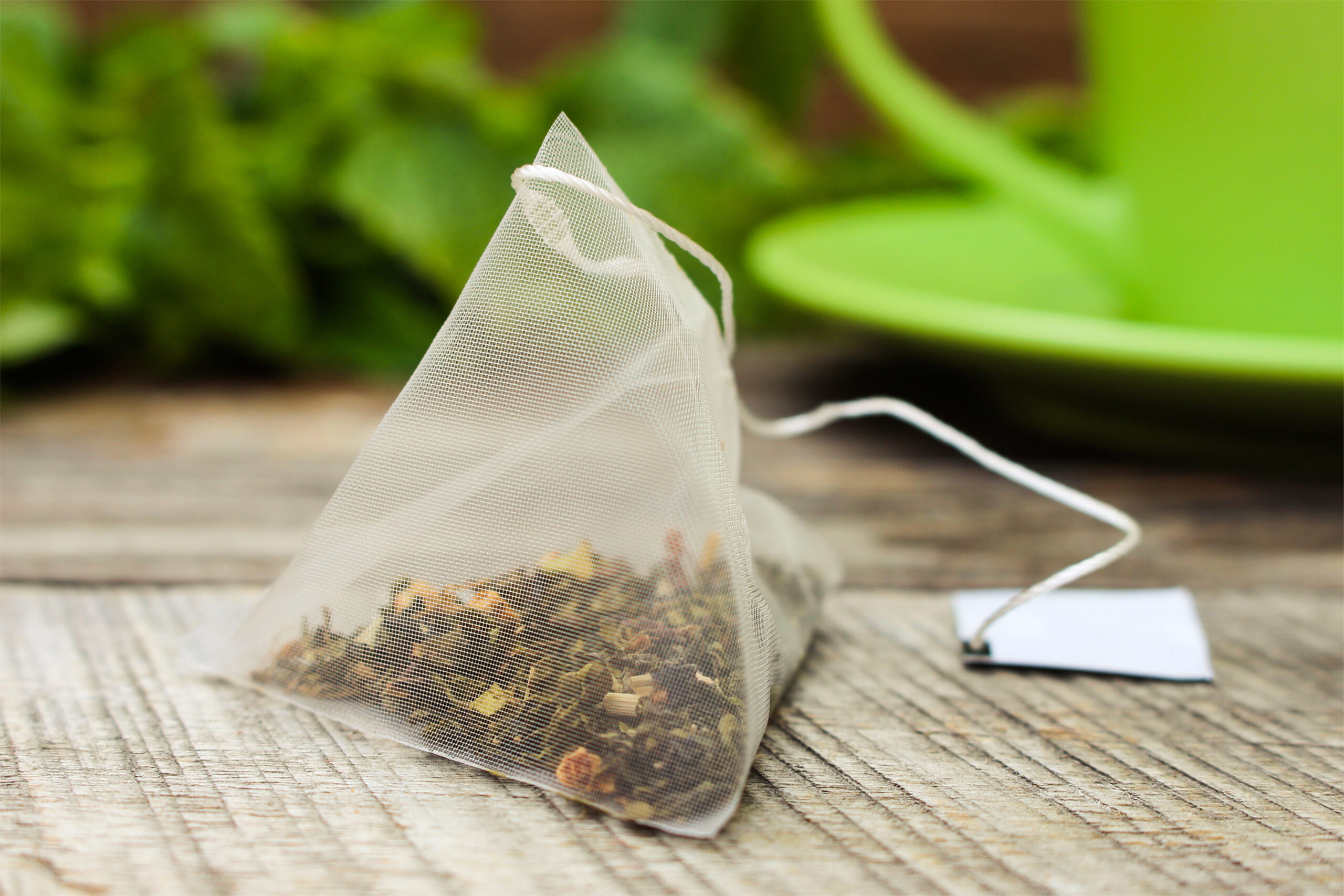 Tea bag on background of mint and and green cup