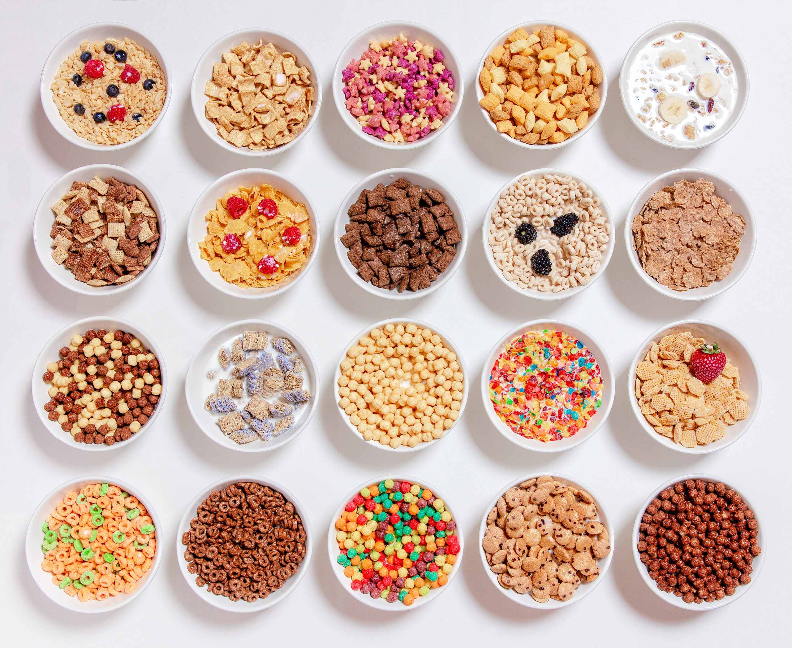 20 bowls with cornflakes, kashi, cereals and berries. flat lay, top view, white background