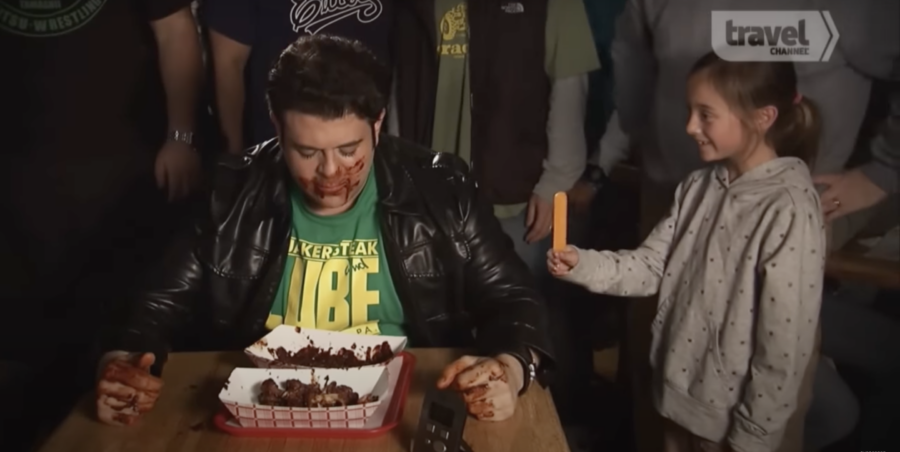 Adam, host of Man v. Food, eating wings as part of the Hellfire Challenge. From Travel Channel's YouTube video, "Hellfire Wing Challenge | Man v. Food | Travel Channel"