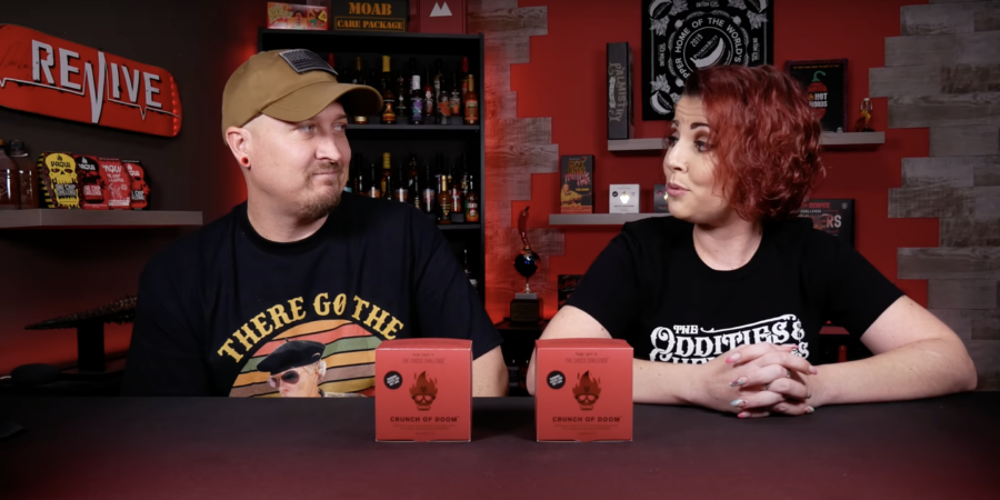 Image of a man and a woman at a table with boxes of Choco Loco in front of them. From YouTube video "Choco Challenge 3.0 Crunch of Doom!!" by HEAT 101