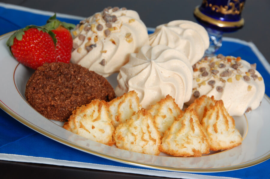 A selection of freshly baked kosher-for-Passover desserts: coconut macaroons, traditional meringues, and meringues covered with chocolate chips and walnuts.