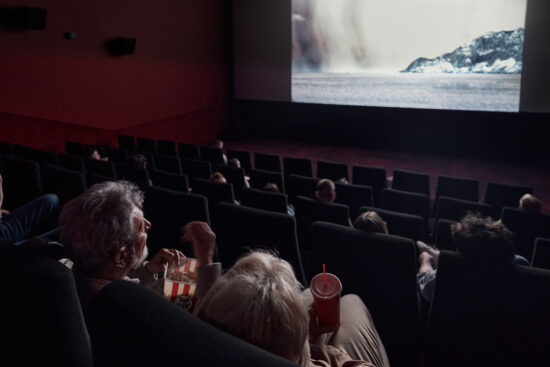 Back view of a mature couple watching a movie in cinema.