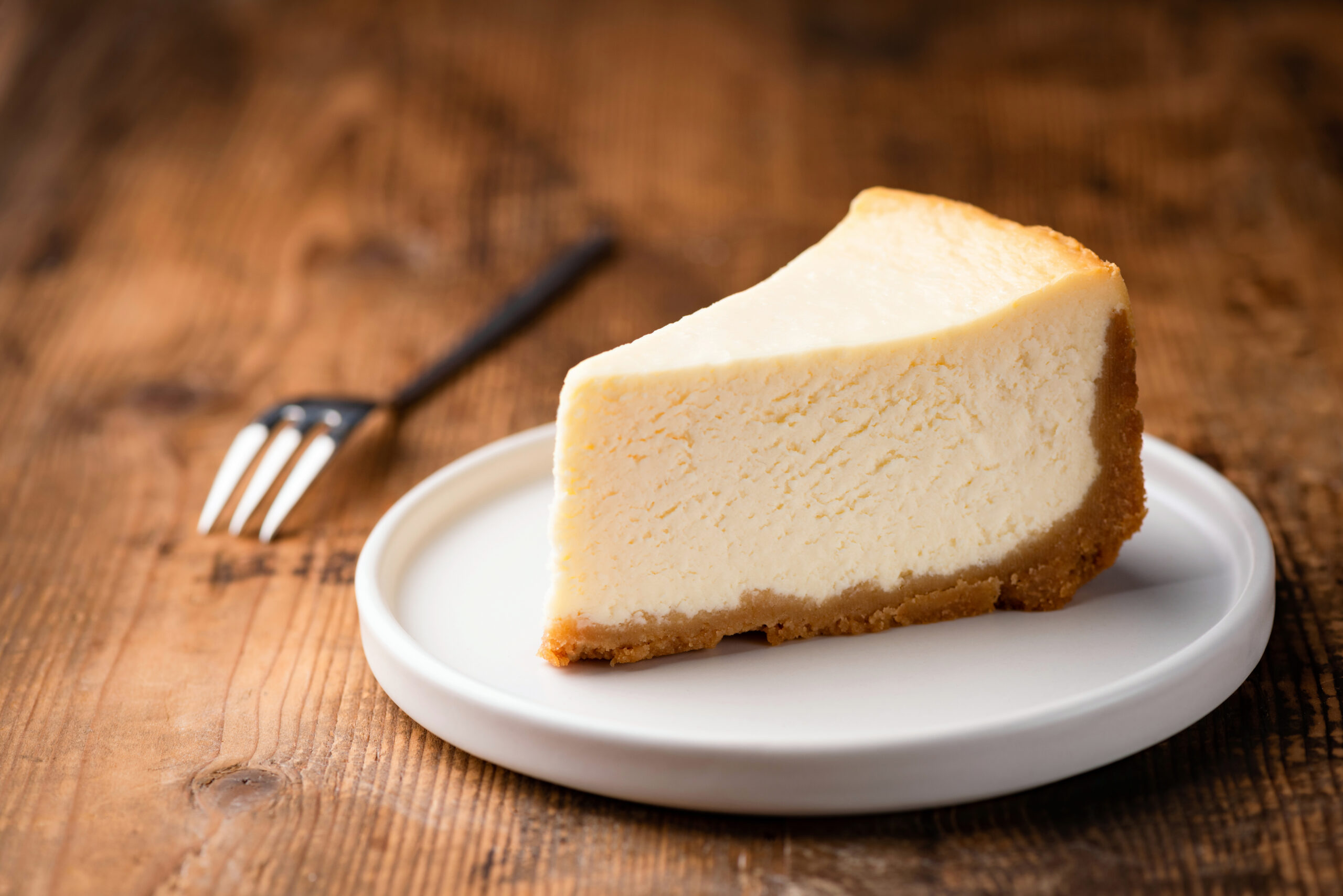 Cheesecake slice, New York style classical cheese cake on wooden background.