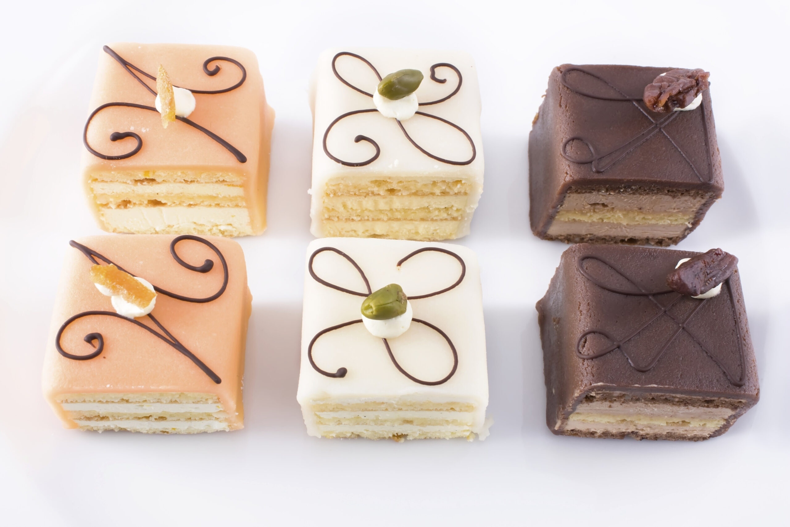 Close up of six petits fours on white plate.