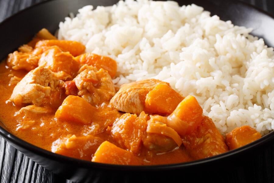 Domoda: a peanut stew made with meat pumpkin and served over fluffy rice close-up in a plate on the table. Horizontal