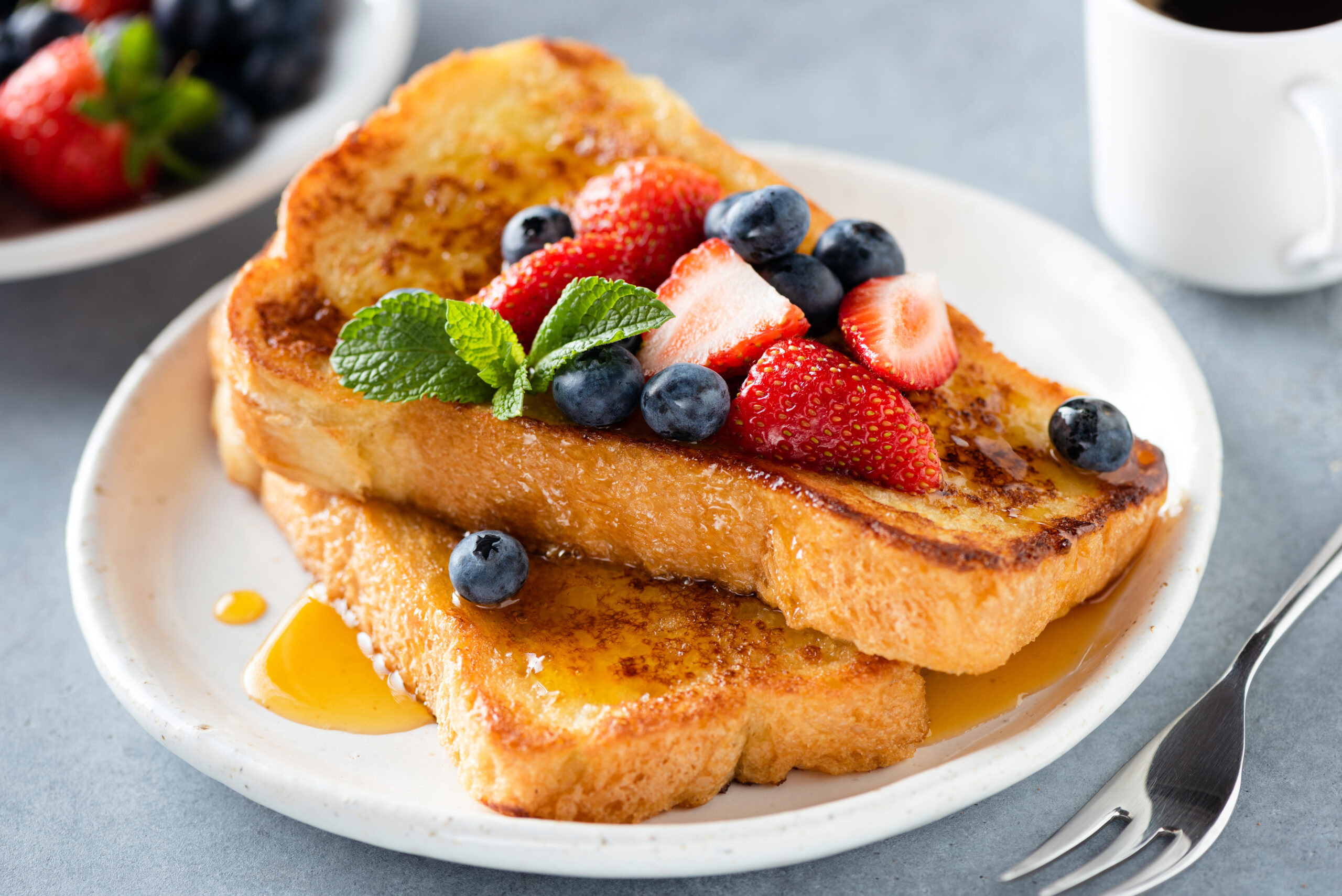 French toast with honey and berries on plate. Sweet breakfast or snack food. Brioche french toast