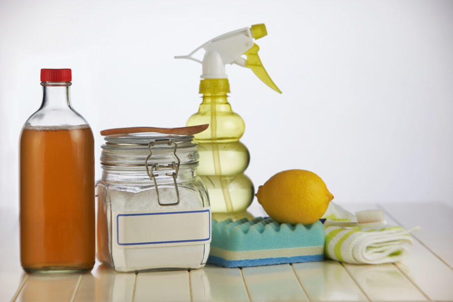 jar of baking soda, sprayer bottle, lemon, sponge, vinegar