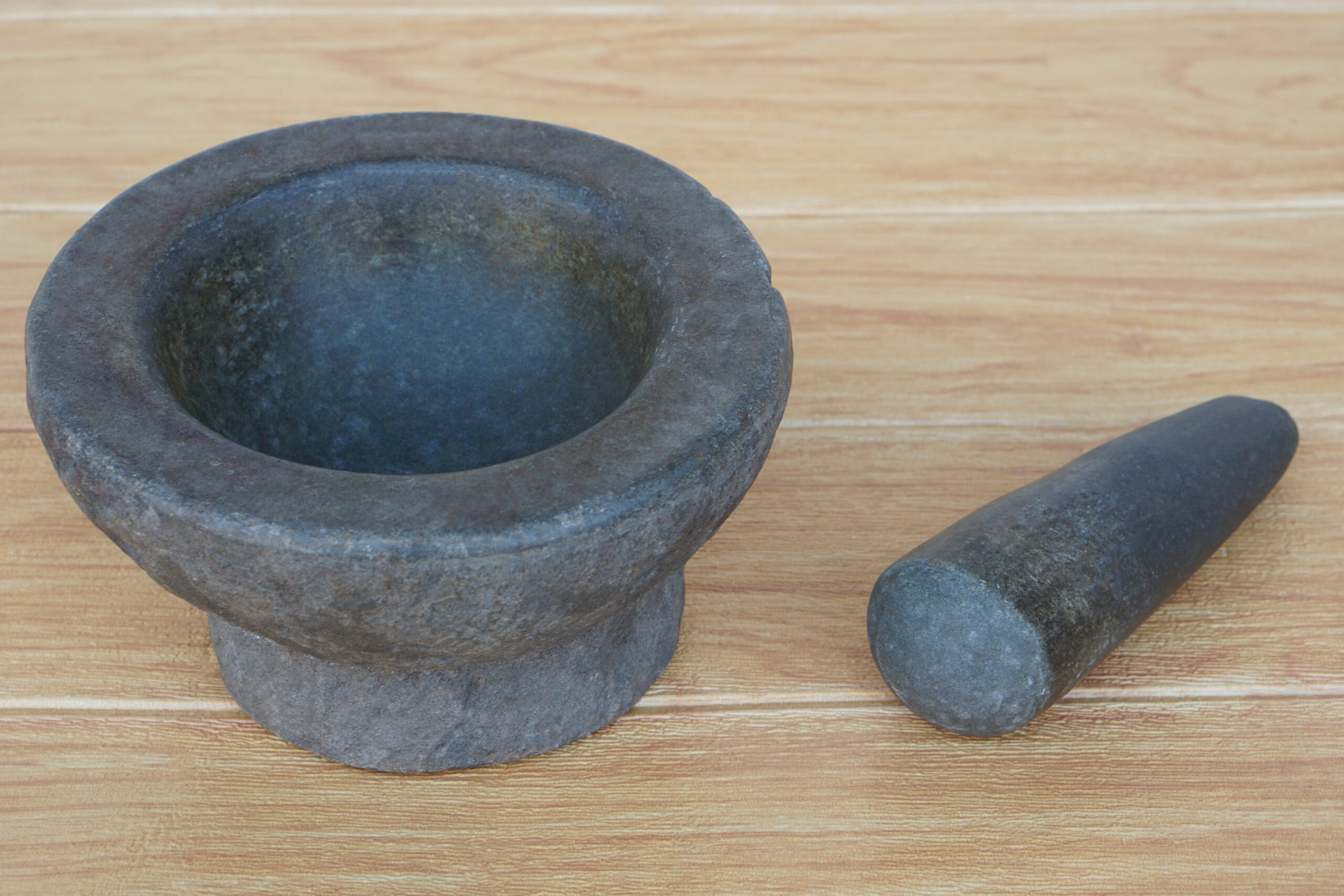 Granite mortar and pestle on wooden background. Stone mortar is an important tool for Thai people to make curry paste. Every family will have a mortar and pestle in the kitchen.