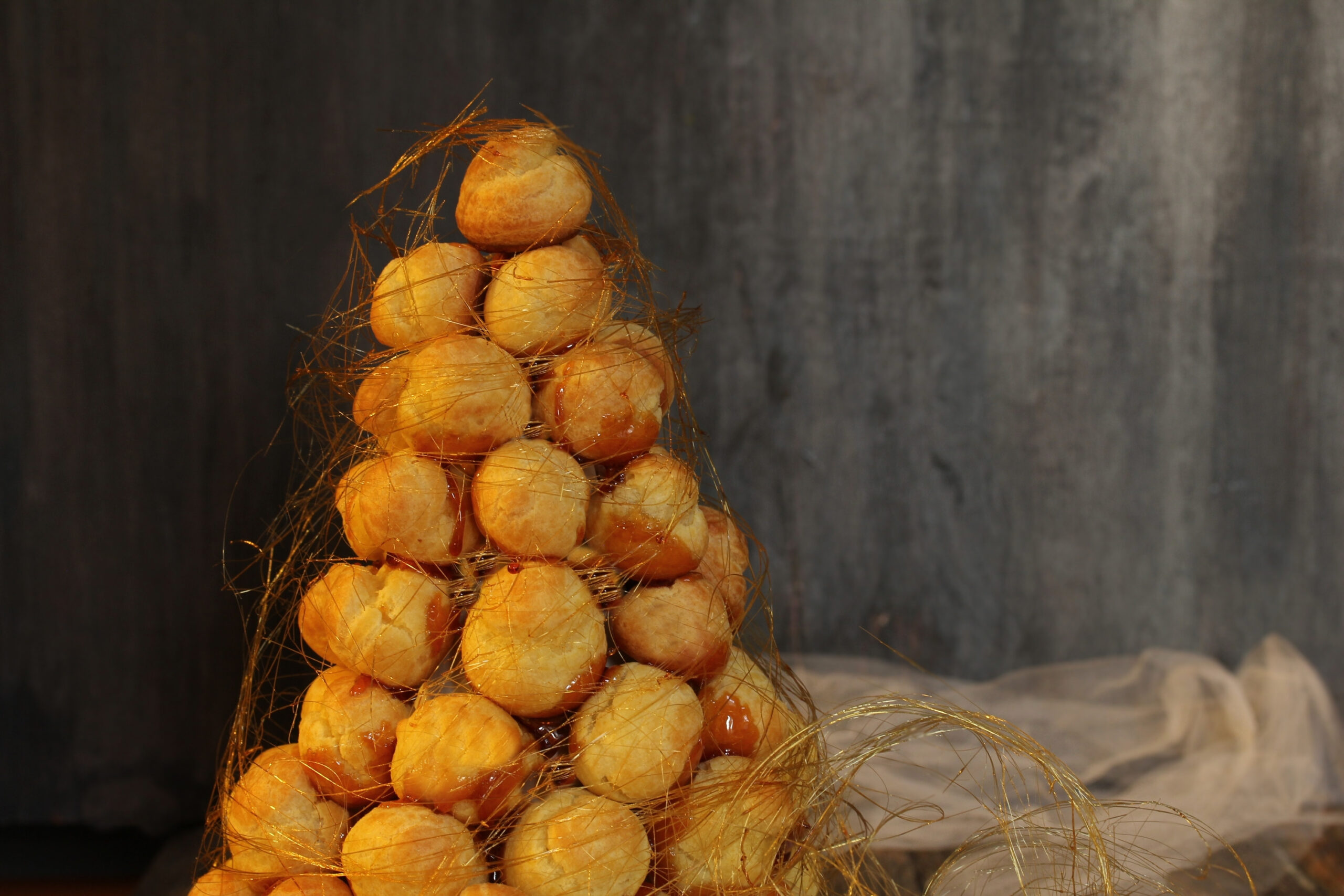 Homemade Crockenbush or Profiterole tower wrapped in spun sugar  on dark moody background, selective focus