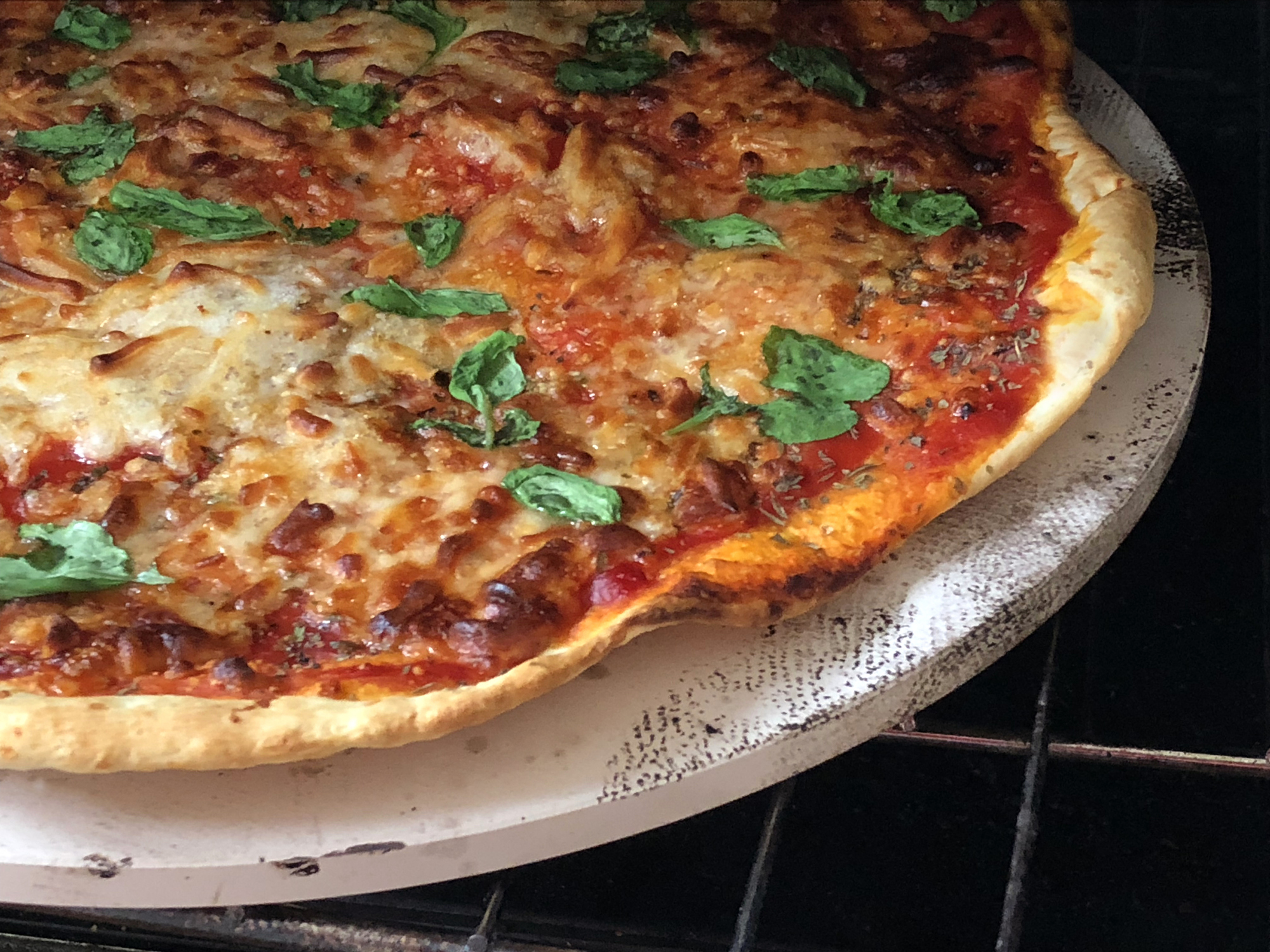 Stock photo of baked homemade pizza recipe with freshly made dough and tomato sauce topping, cooked on pizza stone for thin and crispy base, Neapolitan margherita / margarita pizza.