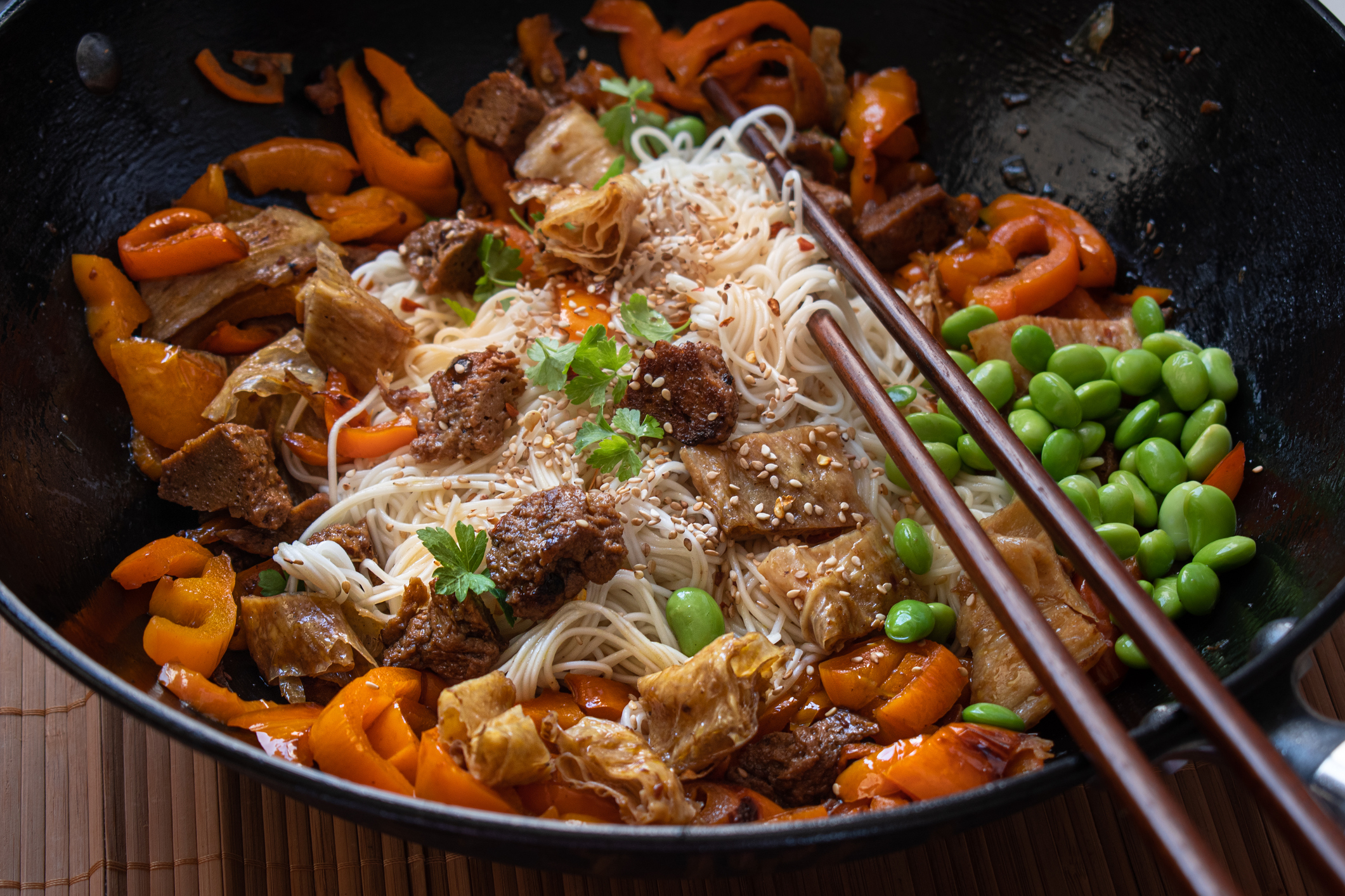 Vegan Stir Fry with yuba, seitan, bell pepper, edamame. "nWheat noodles, served in wok