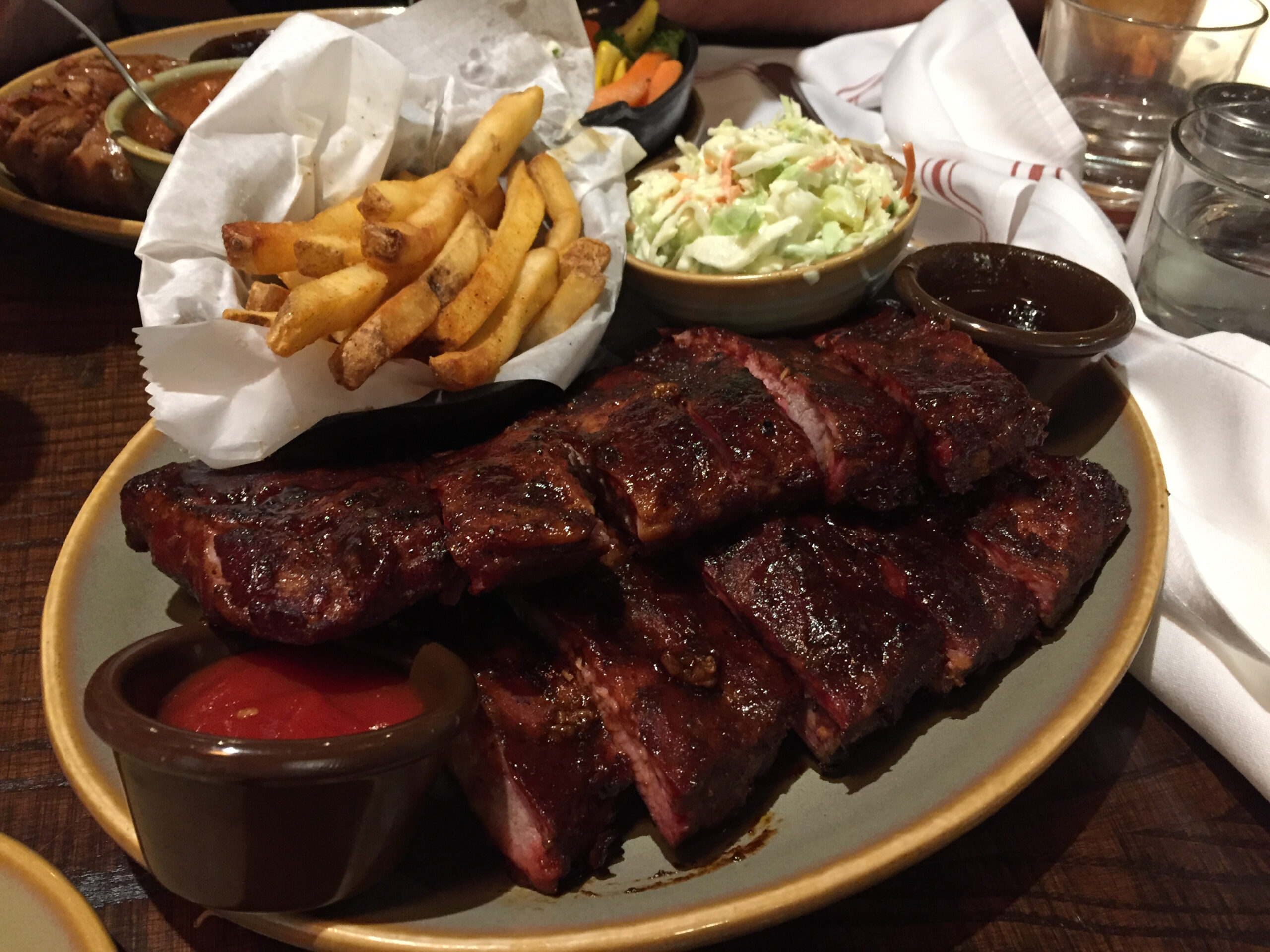 BBQ platter with a rack of ribs, French fries, and cole slaw with a side of ketchup.