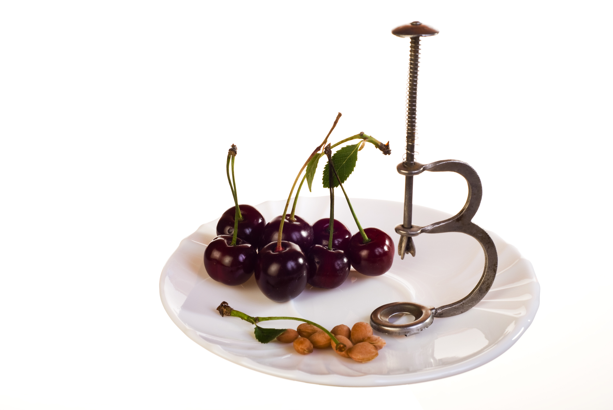 Cherries, cherry pits and pitter on the plate with a vintage cherry stoner