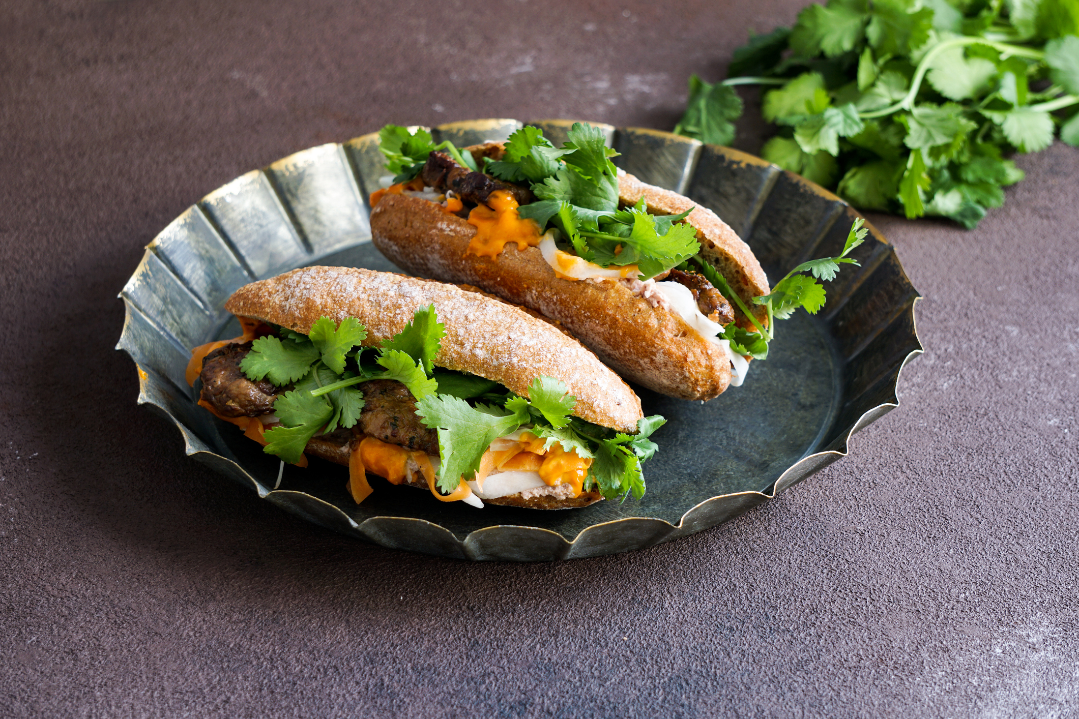 Banh Mi Sandwich,  typical Vietnamese sandwich, coriander leaf, pate, meat, cucumber, pickled carrots, and pickled daikon, on the banana leaf