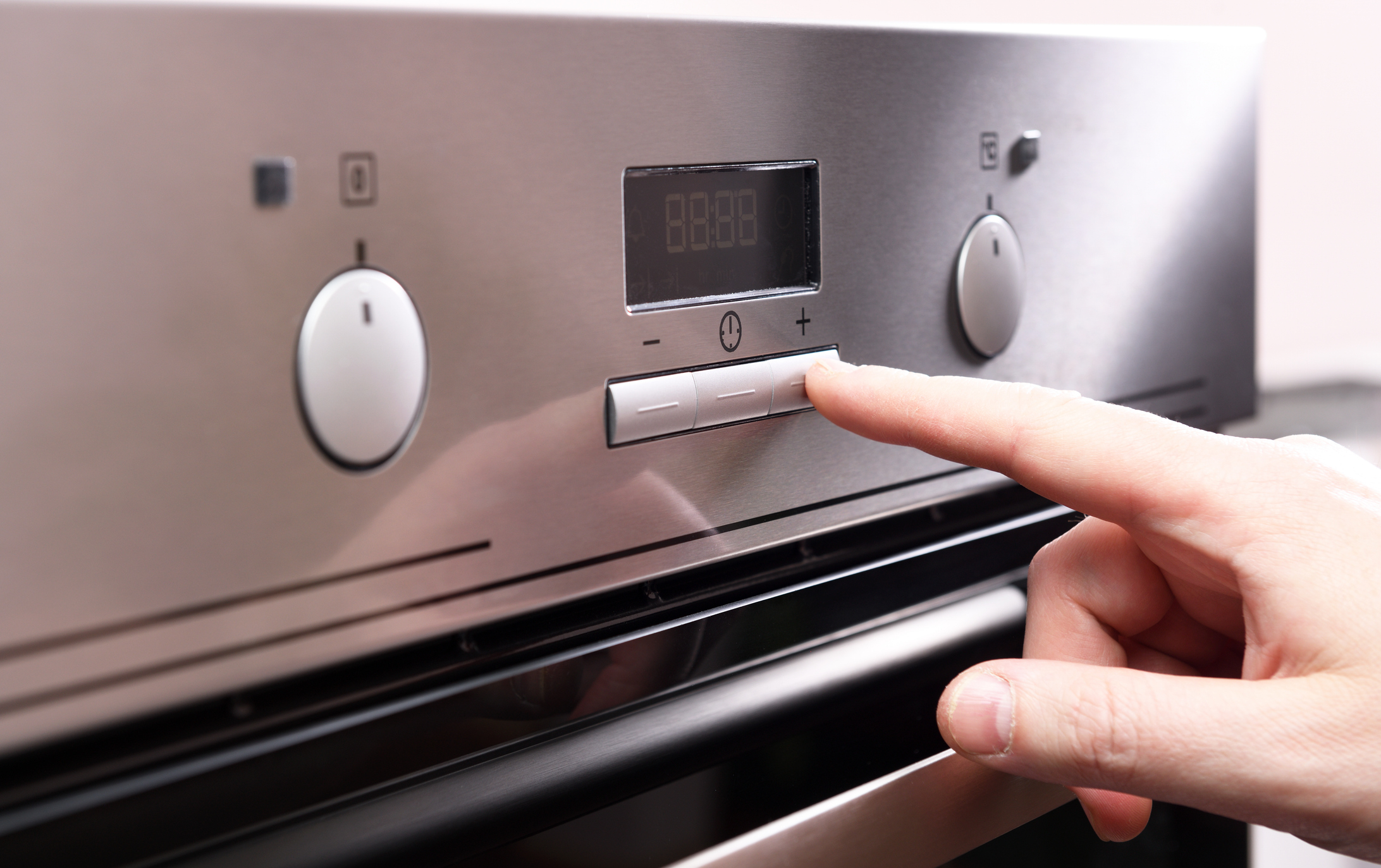 Male finger press button on control panel on oven The control panel of the electric oven.