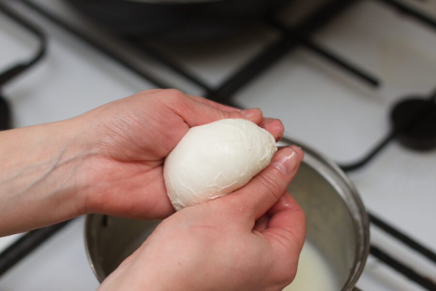 Woman in the kitchen preparing mozzarella cheese at home