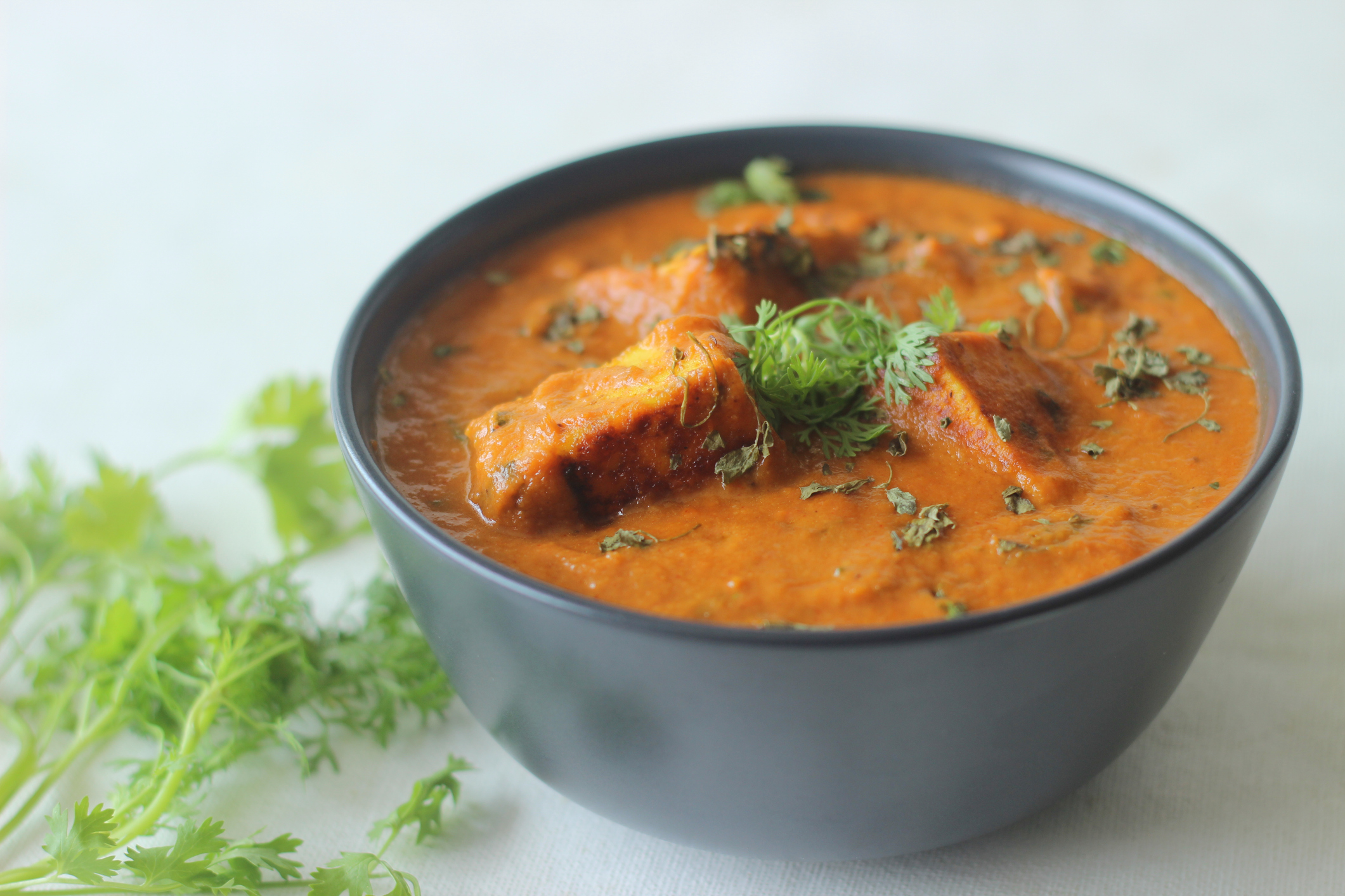 Paneer masala. A curry made with cottage cheese cubes cooked in a gravy of onions tomatoes and spices and garnished with dried fenugreek leaves. Shot on white background