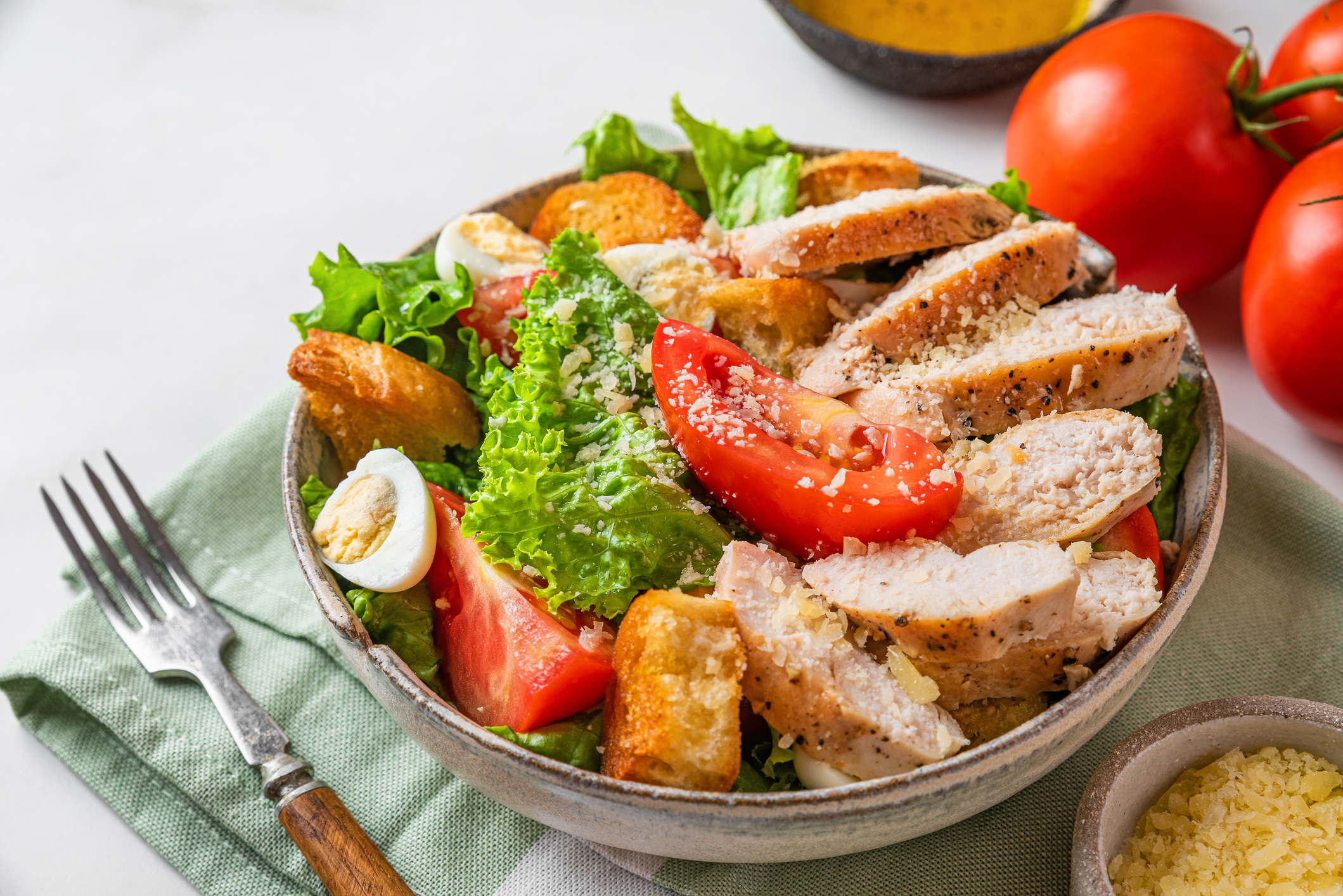 Caesar salad. Healthy salad made of chicken breast fillet, lettuce, tomatoes, quail eggs, croutons, parmesan cheese in a plate with fork