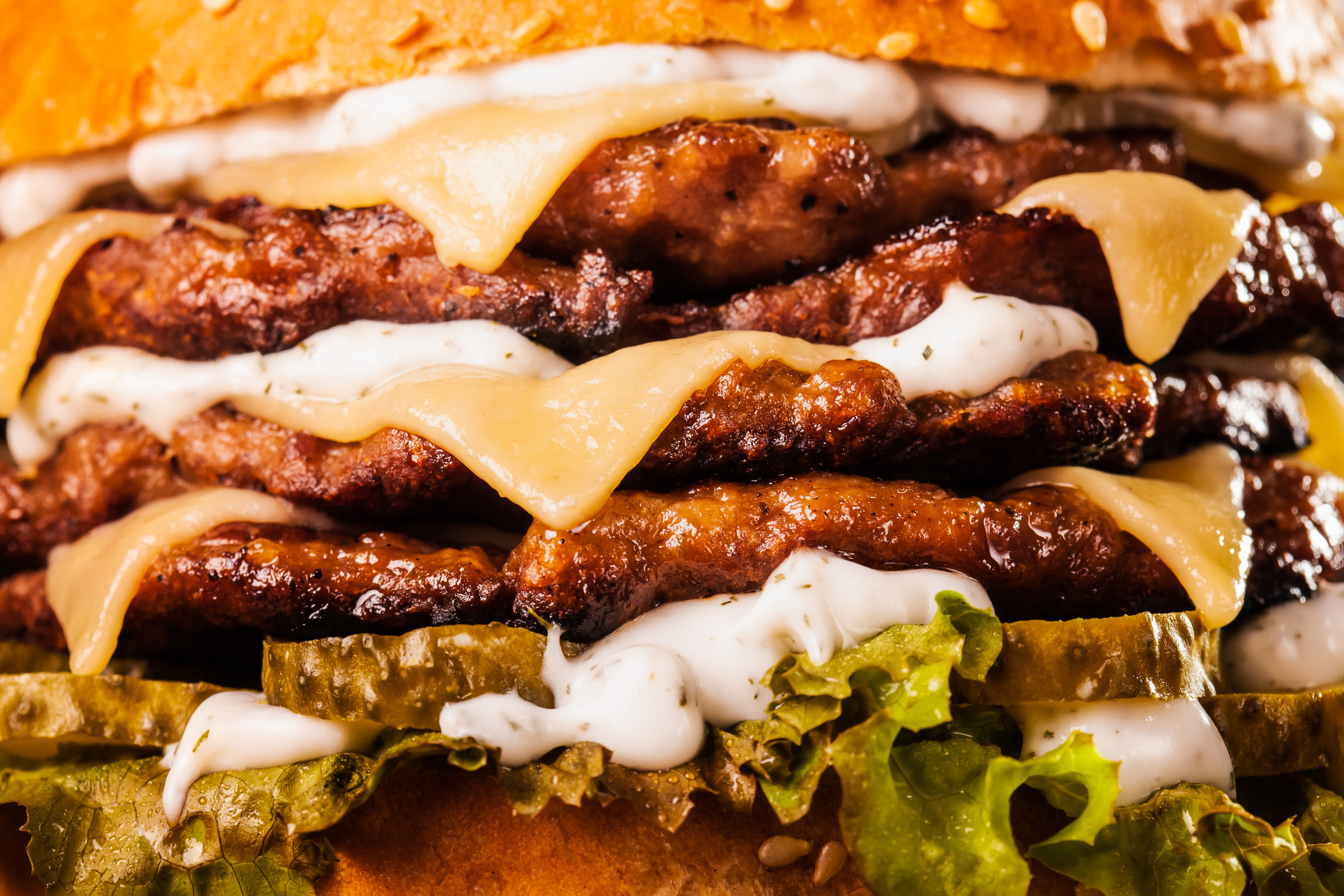 Abstract junk food. Quadruple burger with cheese cucumber and lettuce. Fast food background texture.