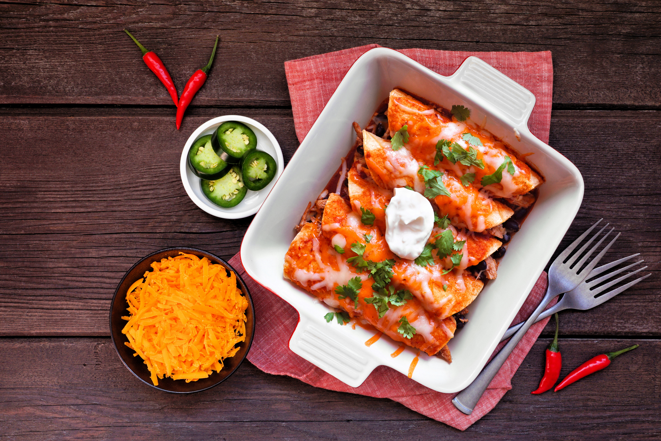 Chicken enchiladas with black beans. Mexican food dish. Top view table scene on a dark wood background.