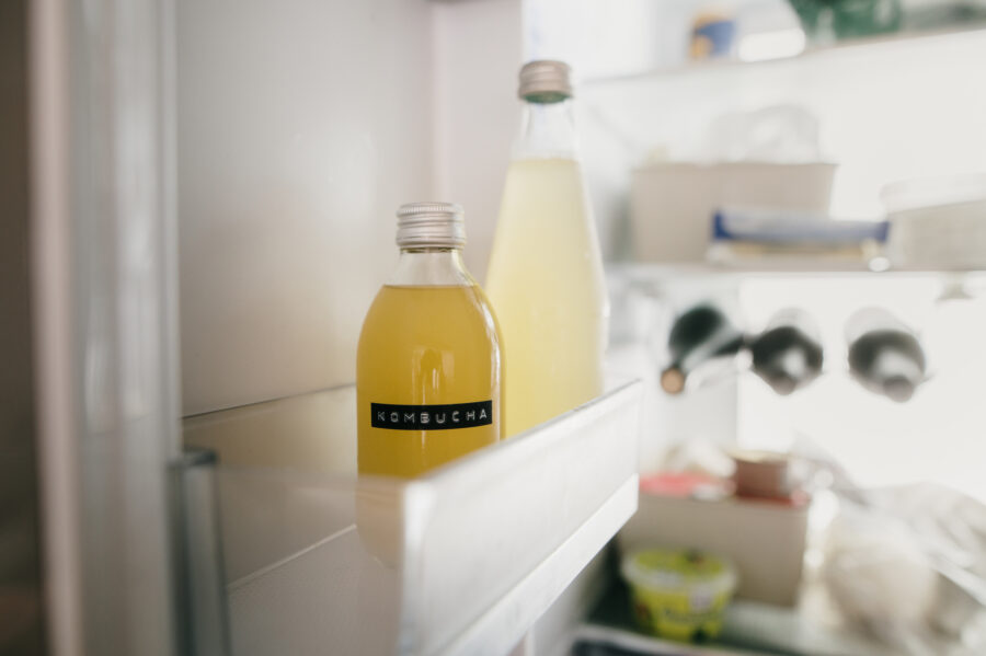 A small glass bottle of kombucha in a fridge